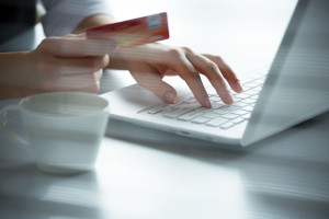 Business woman holding credit card and using laptop.