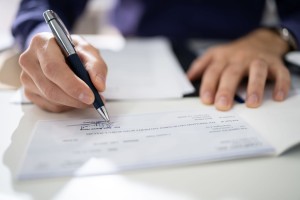 135482082 - close-up of human hand writing on cheque